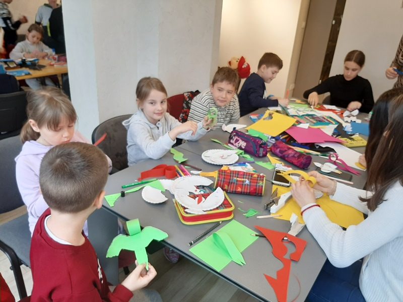 Otroci izdelujejo ptičke iz papirja.