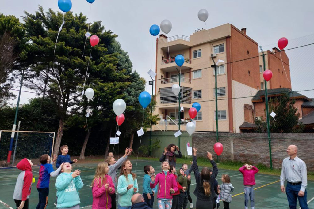 Otroci in učitelji na šolskem dvorišču praznujejo dan državnosti. V zrak so spustili modre, bele in rdeče balone