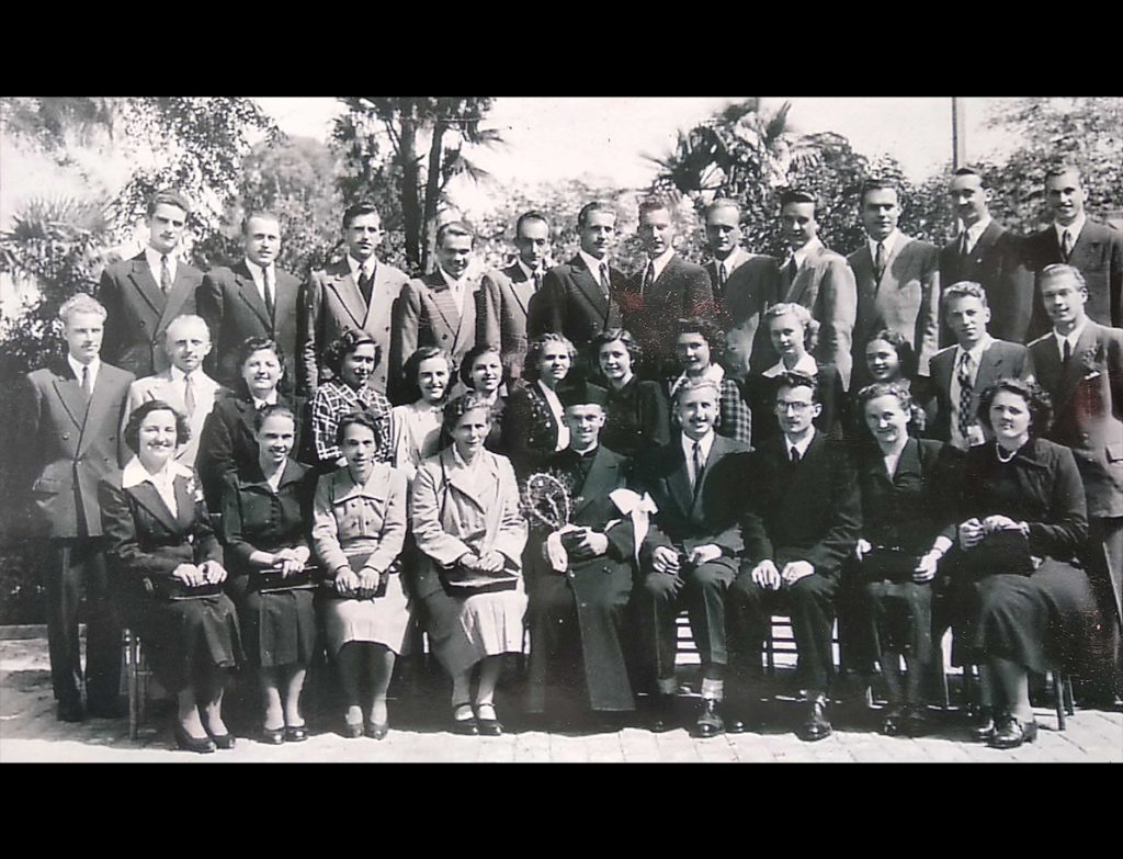 Črno-bela skupinska slika pevk in pevcev zbora, skupaj z zborovodjo