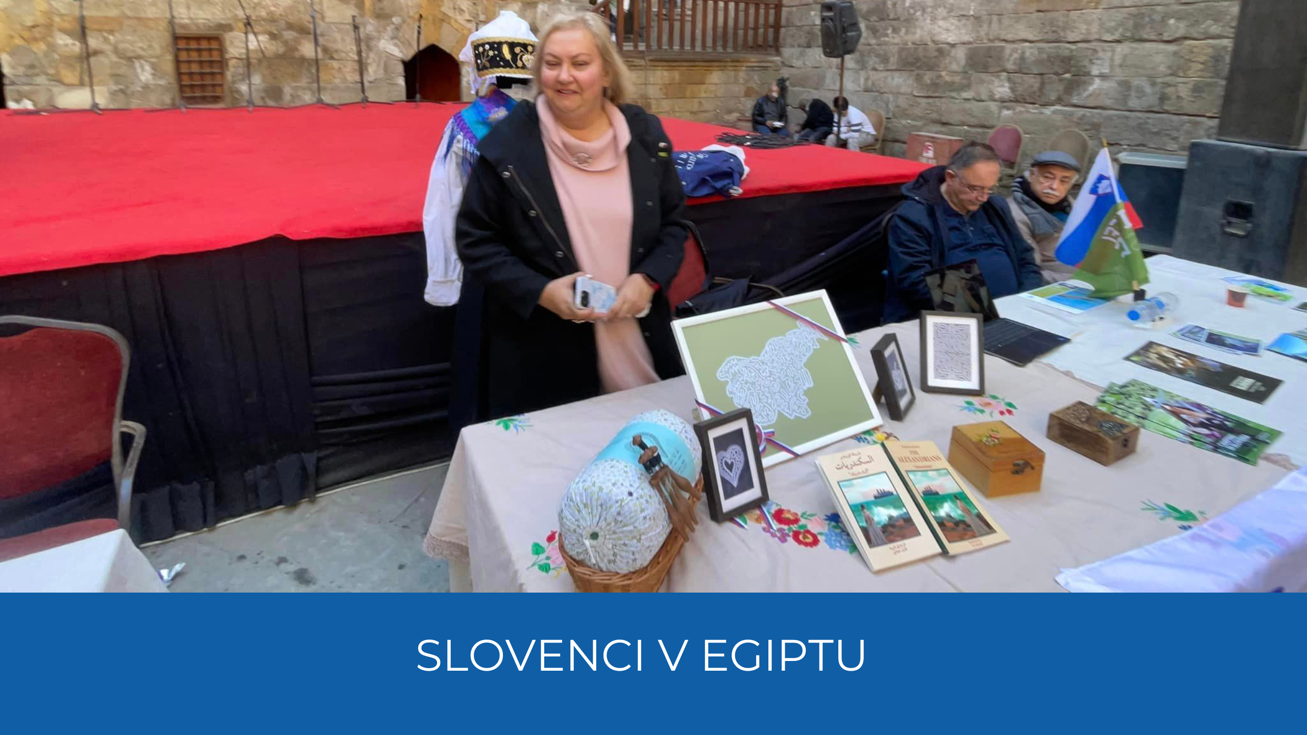 Salwa Hegazi stoji za mizo z razstavo o Sloveniji