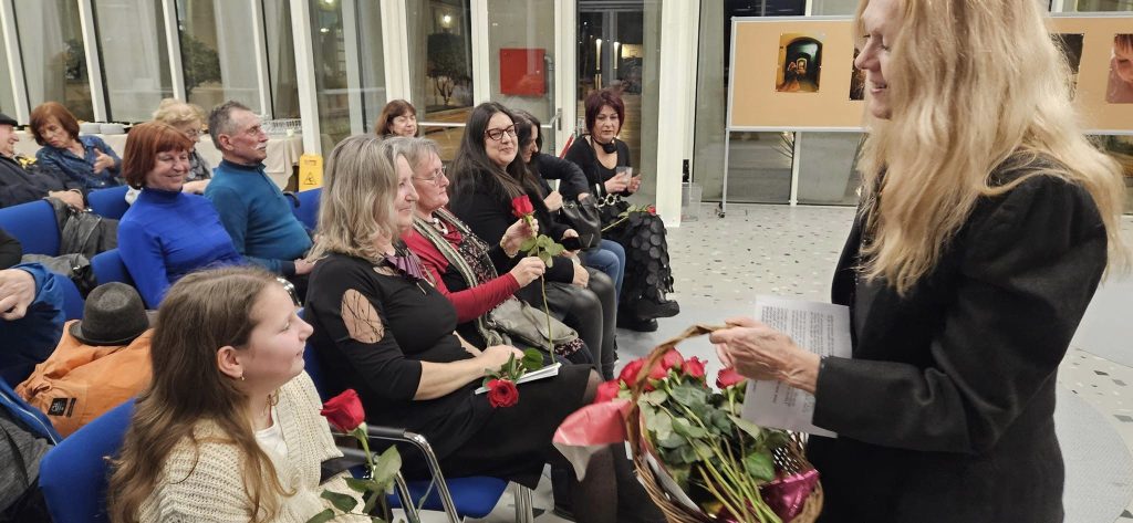 Ženska udeležencem razstave deli rdeče vrtnice