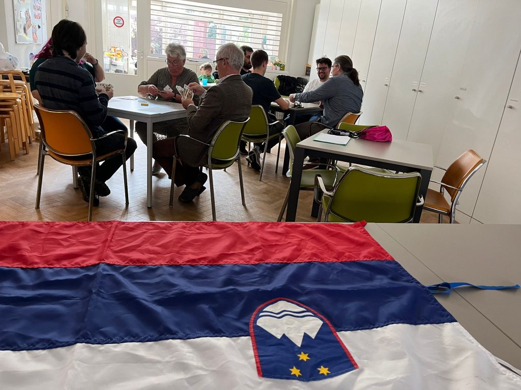 Slovenska zastava na mizi in v ozadju mize, kjer se igra tarok