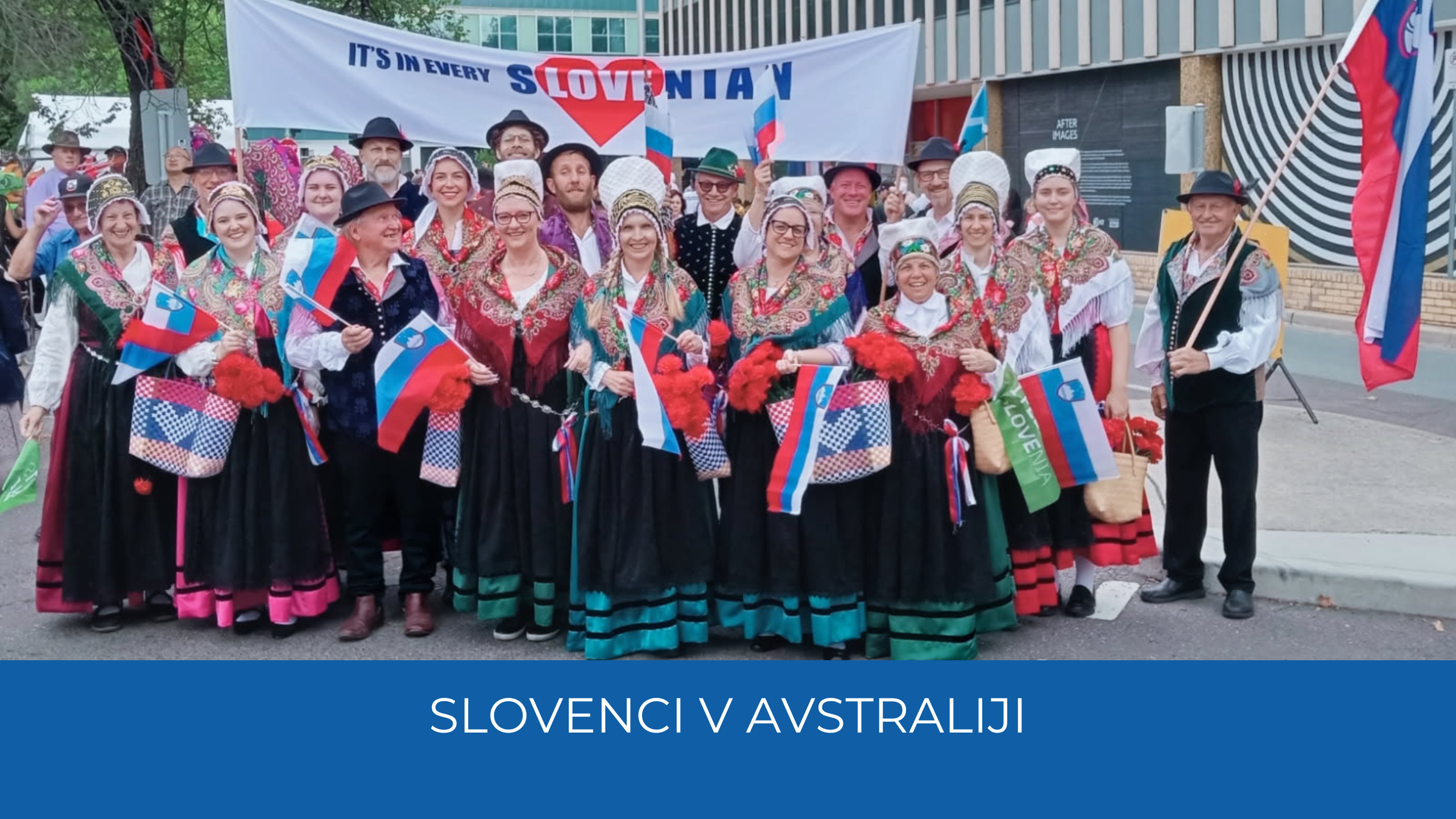 Rojaki oblečeni v noše, v rokah držijo slovenske zastave. V rokah držijo tudi transparent na katerem piše "It's in every Slovenian". Spodaj moder trak, na njem napis Slovenci v Avstraliji.