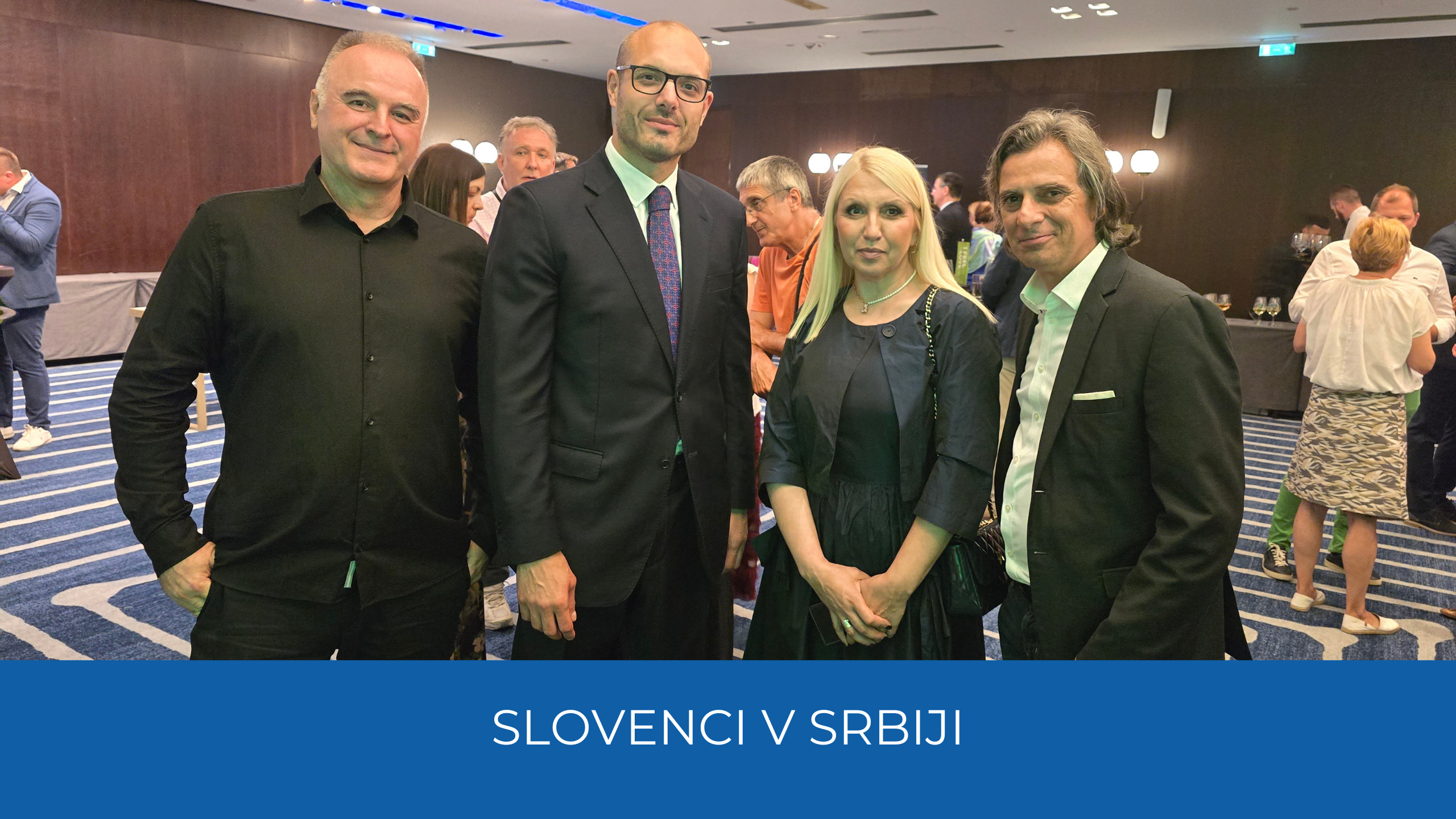 Udeleženci sprejema, spodaj modra črta na njej napis Slovenci v Srbiji.