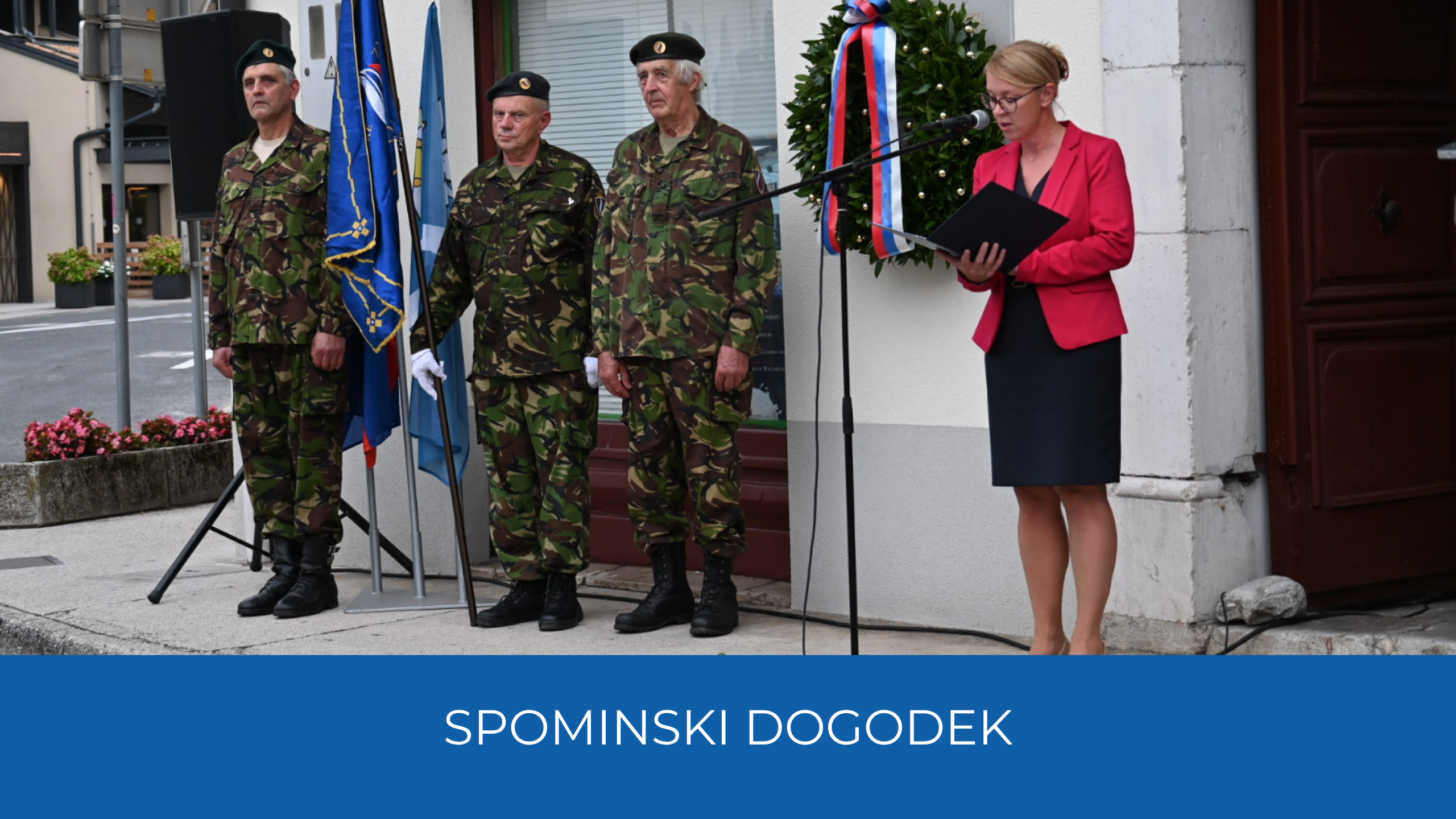Državna sekretarka med nagovorm, na levi vojaki in zastave ter venec. Spodaj napis Spominski dogodek na modrem traku.