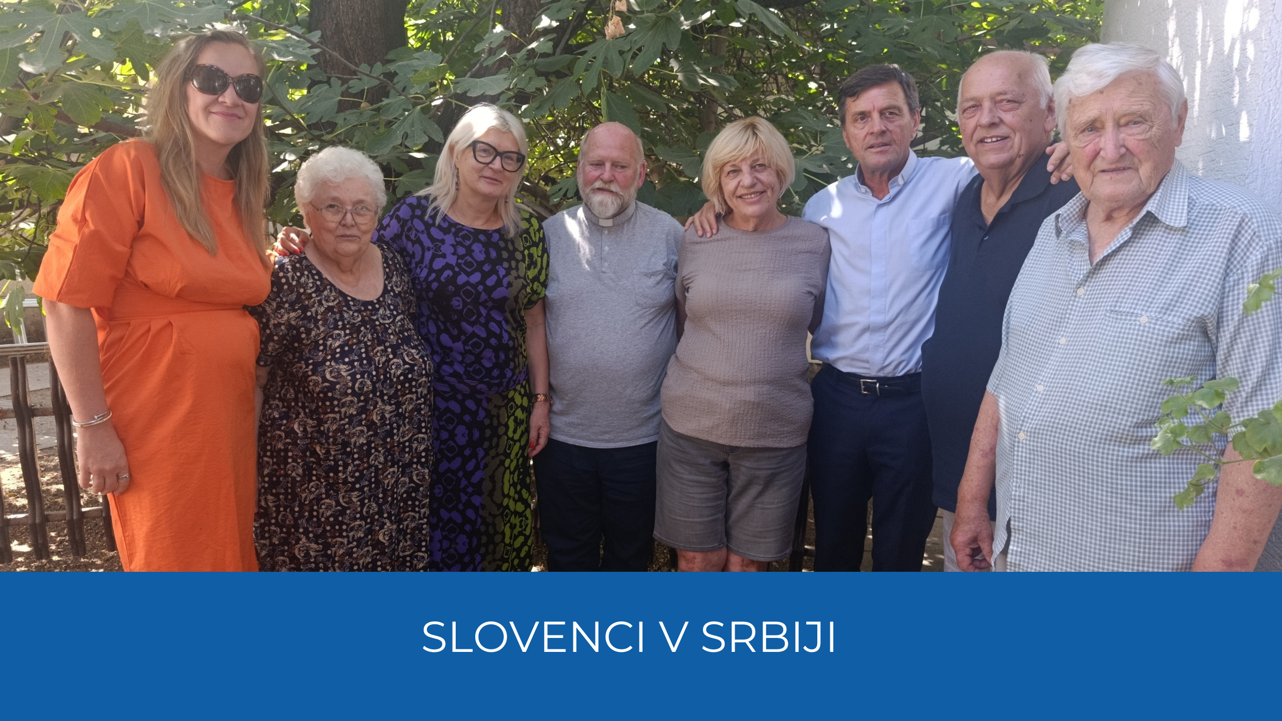 Obiskovalce in gostitelji. Spodaj na odrem traku napis Slovenci v Srbiji.